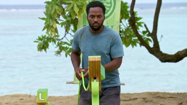 Deshawn Radden competes in a competition where he his holding a green rope and stacking green blocks