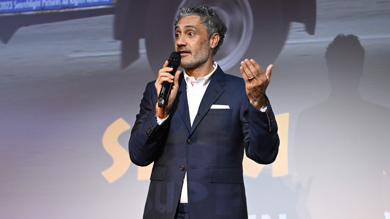 Taika Waititi speaking into microphone