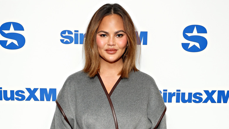 Chrissy Teigen smiling in grey