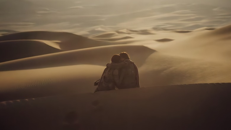 Paul and Chani sitting on sand hill 