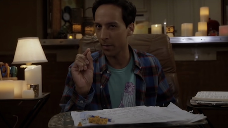 Abed from Community holding dice and a sheet of paper