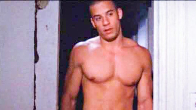 A shirtless Vin Diesel cocks his head