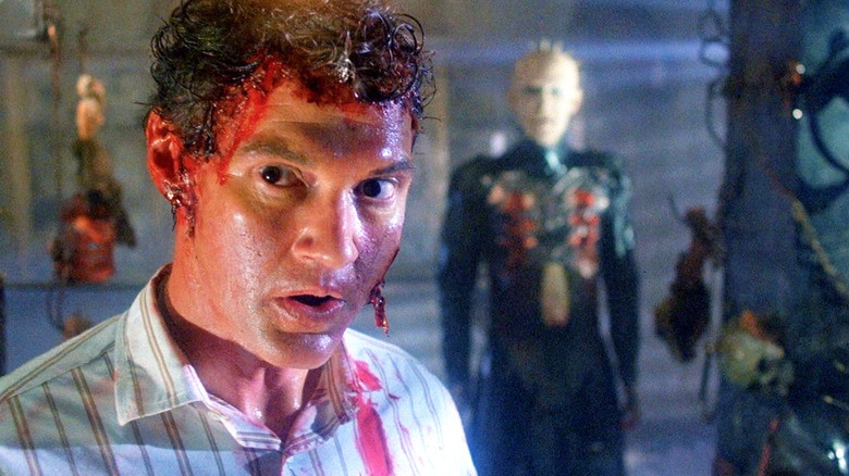 Frank Cotton wearing Larry Cotton's skin, covered in blood, with Pinhead standing in the background