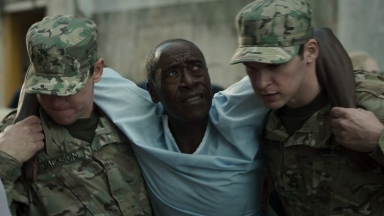 Two soldiers helping Rhodey walk