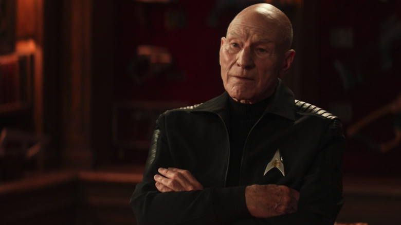 Picard stands in front of a case of weapons