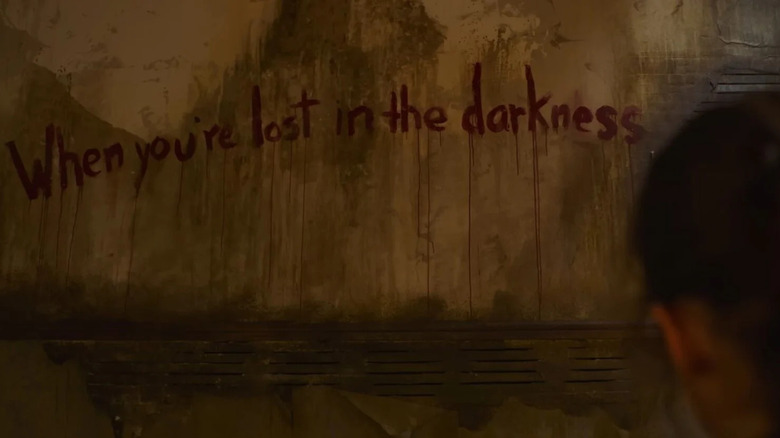 Ellie looking at "When you're lost in the darkness" painted on a wall