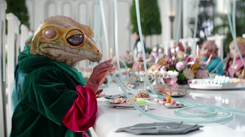A frog alien eats