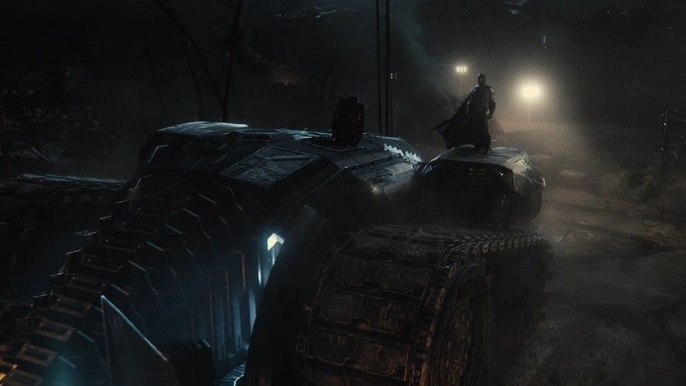 Batman stands on the Batmobile