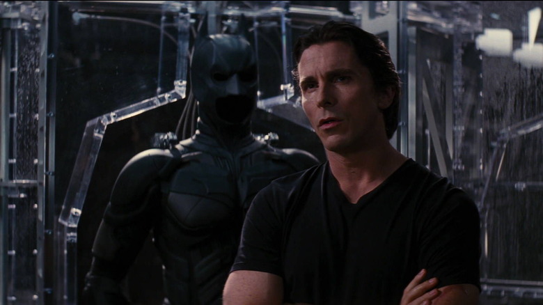 Bruce Wayne in front of a Batsuit