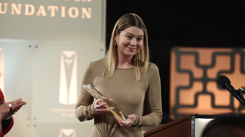 Meredith smirking while holding award