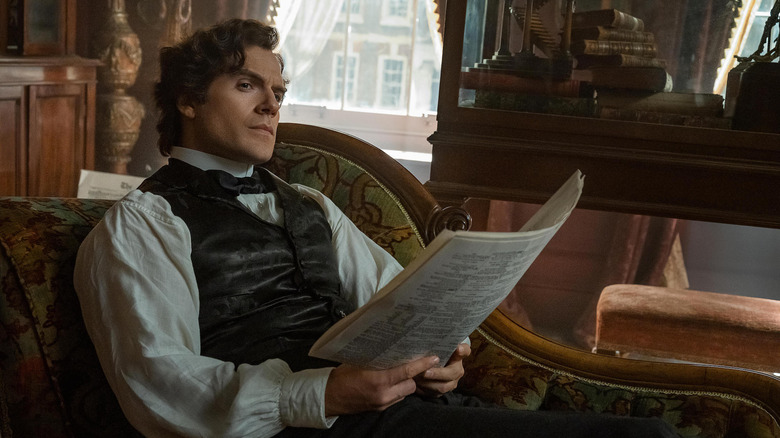 Henry Cavill as Sherlock Holmes looking up from newspaper