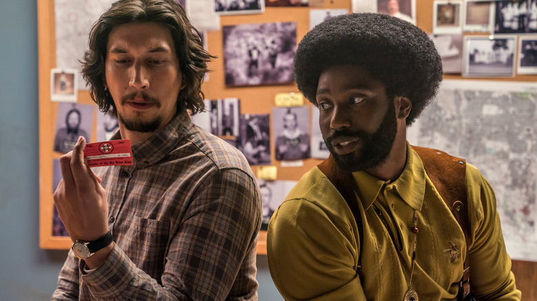 Adam Driver and John David Washington looking at a card