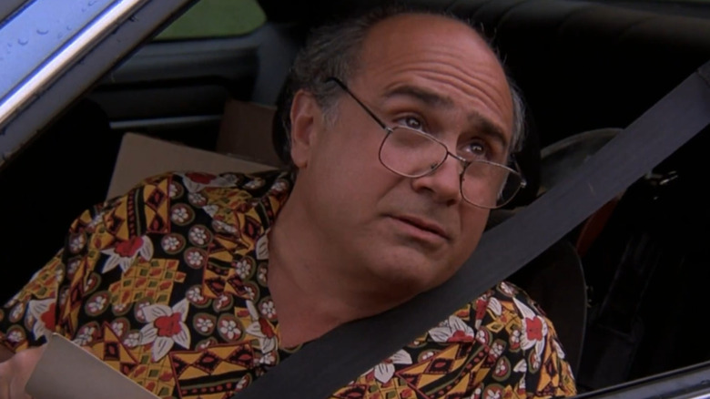 Danny DeVito wears glasses inside a car