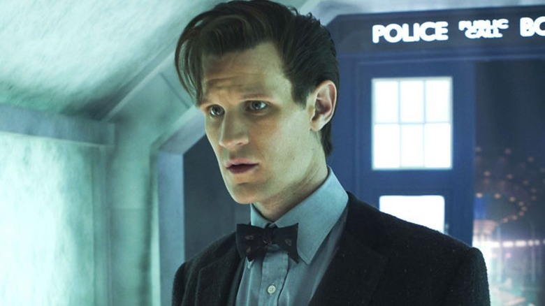 The Doctor stands with the Tardis behind him