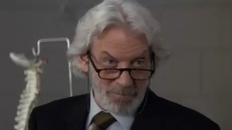 Donald Sutherland with glasses in front of bone display