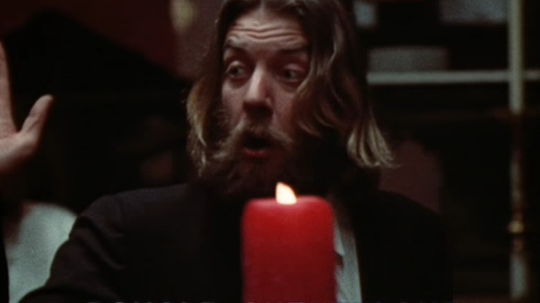 Donald Sutherland raising hand near candle