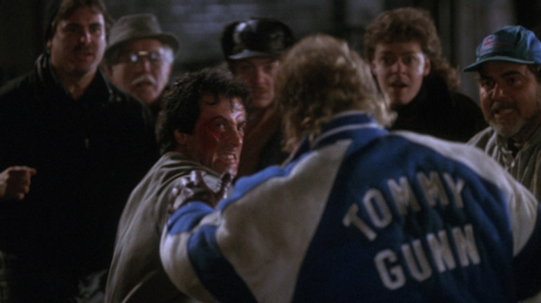 Rocky beats Tommy in the street as a crowd watches