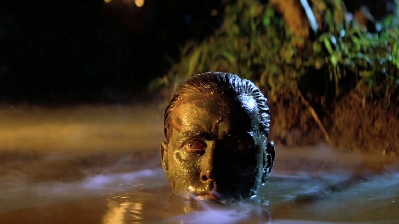 Martin Sheen emerging from the water covered in mud