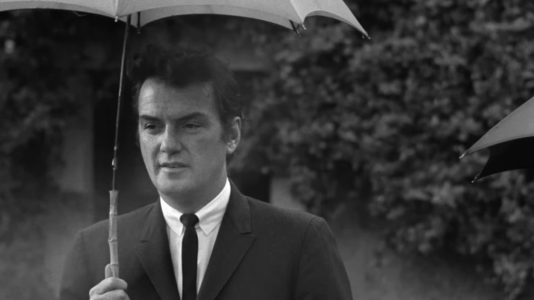 Man in suit holding umbrella in black and white