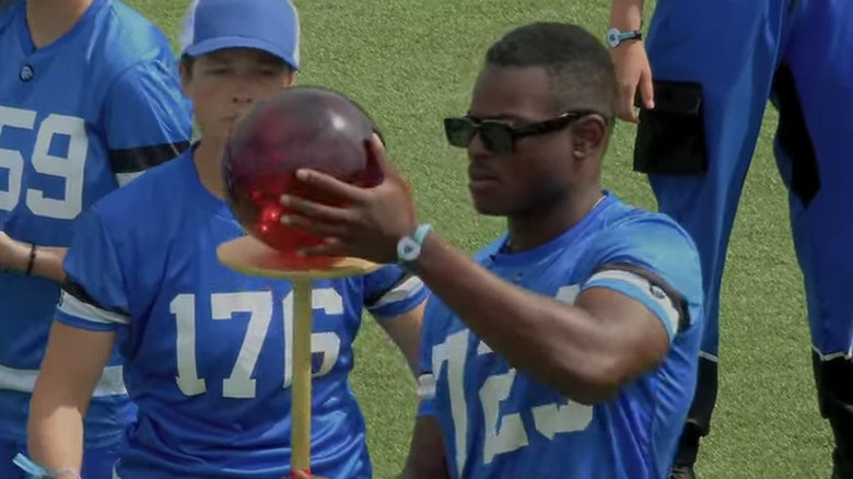 Man holding a glass ball on a pedestal on Beast Games