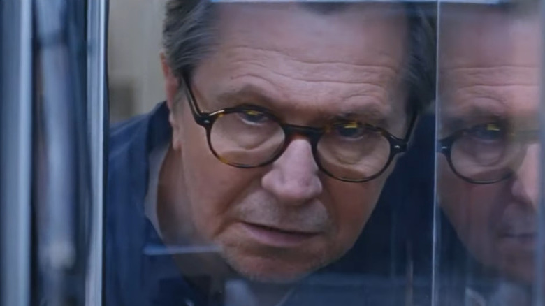 Gary Oldman looks into a cage