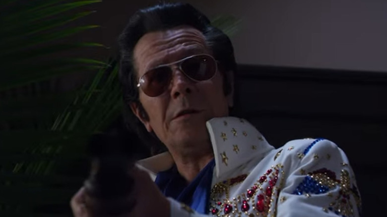 A gun-toting Gary Oldman dressed as Elvis