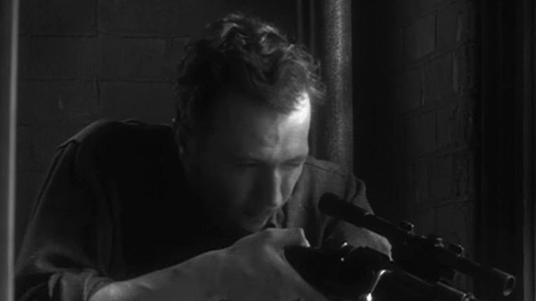 Lee Harvey Oswald looks through a rifle scope