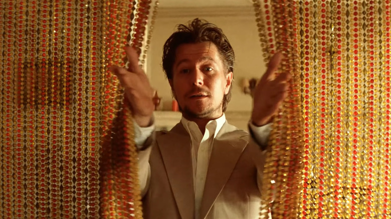 Gary Oldman walks through a beaded curtain