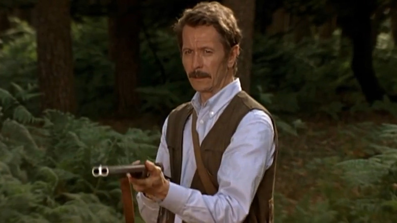 Gary Oldman aims a shotgun