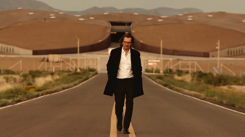 Gary Oldman walks down a road