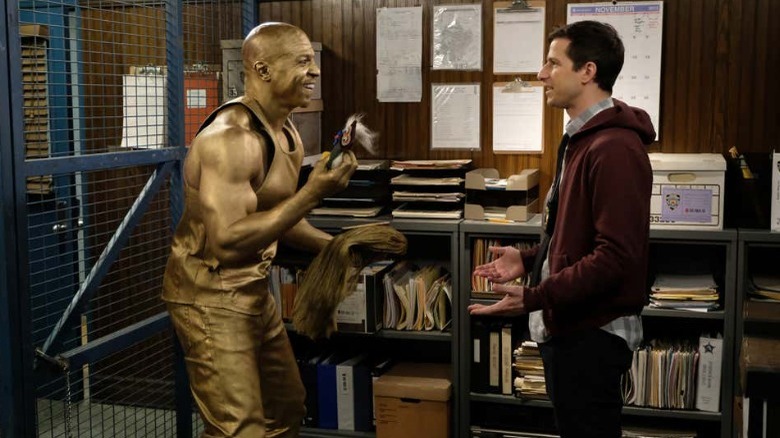 A gold-painted Terry Jeffords talks exictedly with Jake Peralta