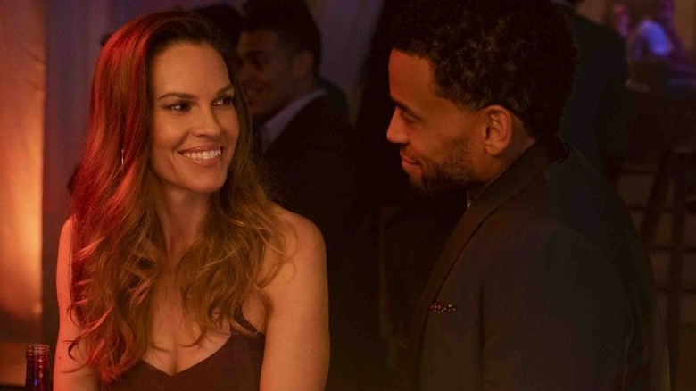 Hilary Swank smiling at a bar while looking at Michael Ealy
