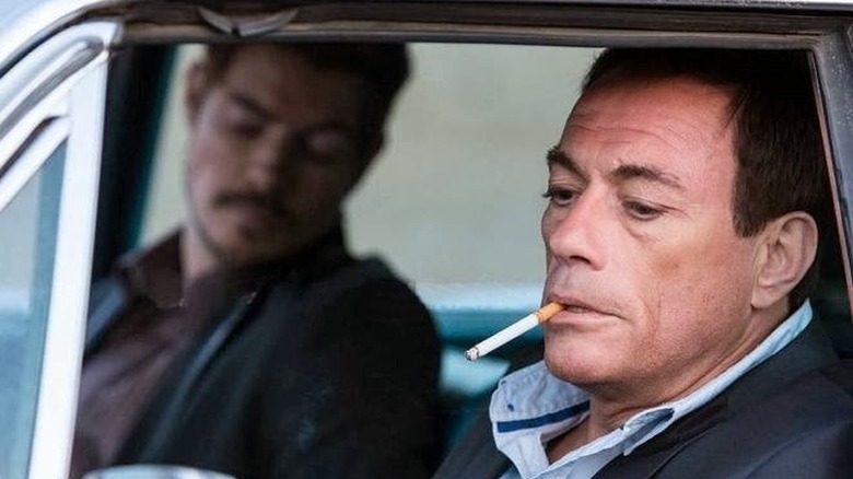 Jean-Claude Van Damme smoking a cigarette in a car