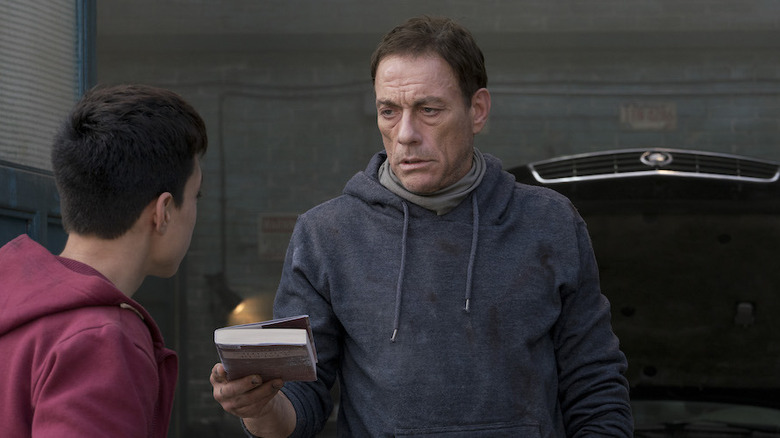 Jean-Claude Van Damme gives a book to a kid