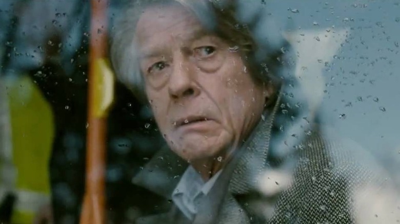 John Hurt looks out a car window in the rain