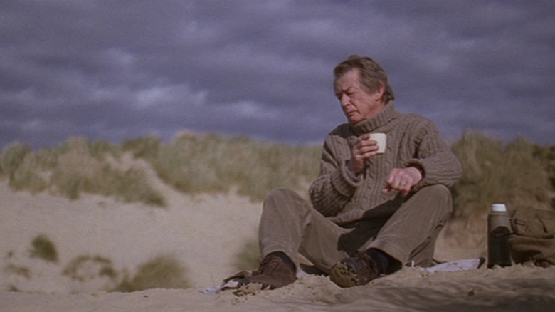 John Hurt sits on a beach