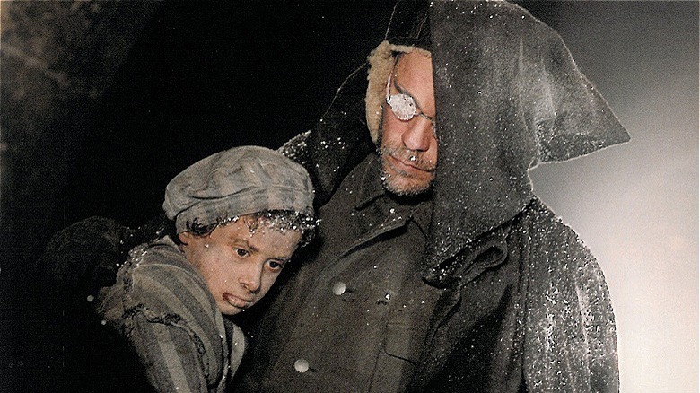 malkovich in black coat carrying a child/the ogre