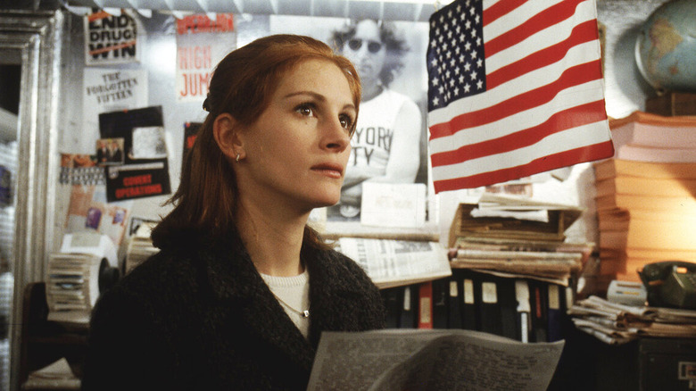 Julia Roberts holding a newspaper and looking up 