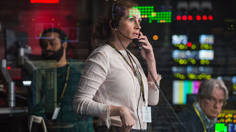 Julia Roberts behind glass on the phone in a producer's booth