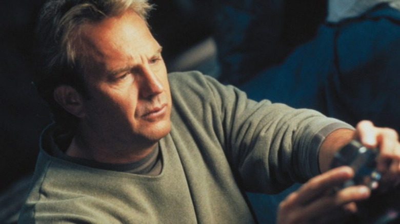 Kevin Costner looking at object