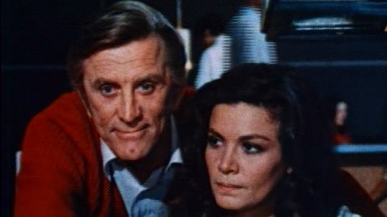 kirk douglas looks over a woman's shoulder