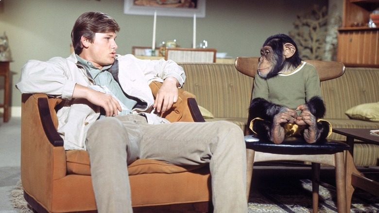 Kurt Russell sits with a chimp