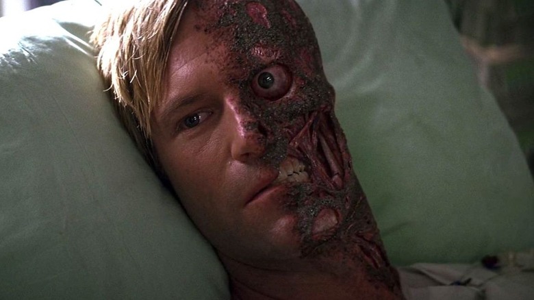 Aaron Eckhart lying in a hospital bed