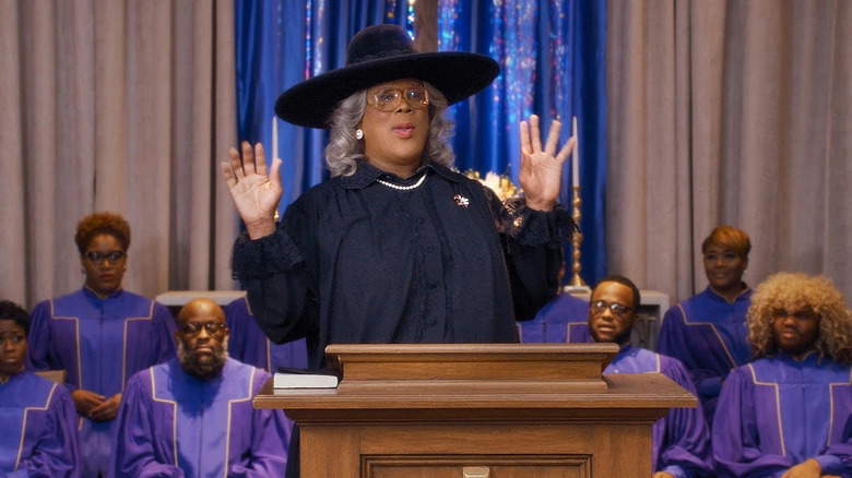 Madea speaking at a funeral with a choir behind her