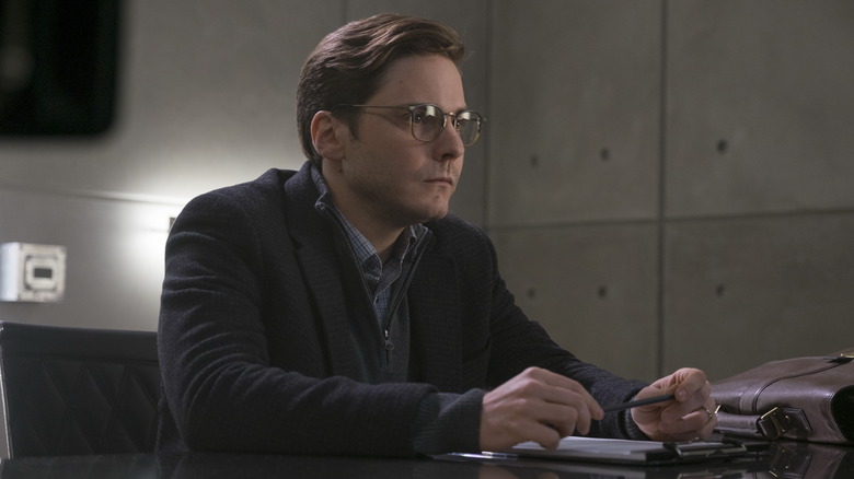 Helmut Zemo plays with a pen as he sits at a desk