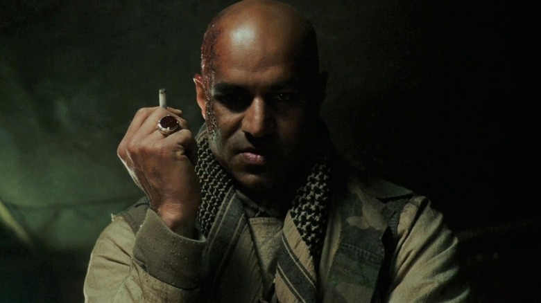 Raza glares while holding a cigarette