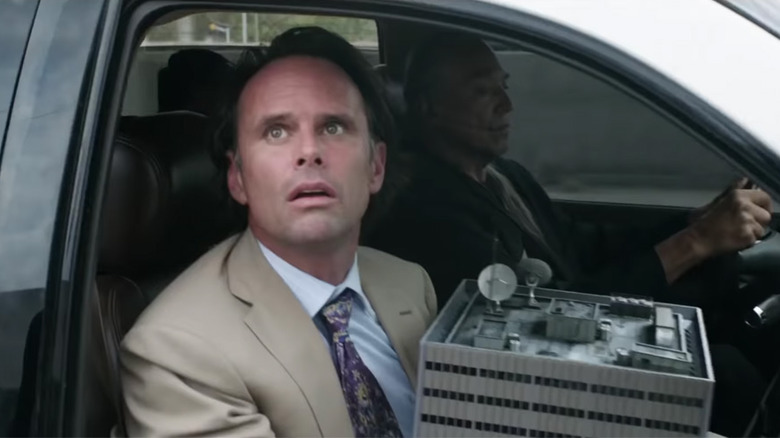 Sonny Burch clutching a small building in the passenger seat of a car