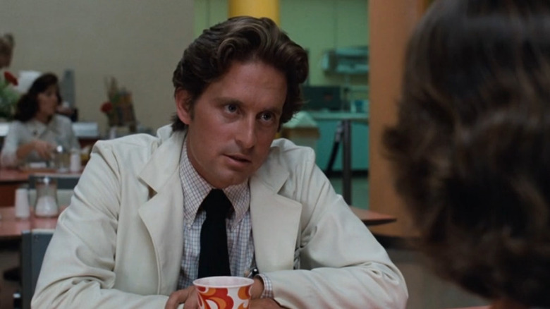 Michael Douglas in a lab coat sitting at table