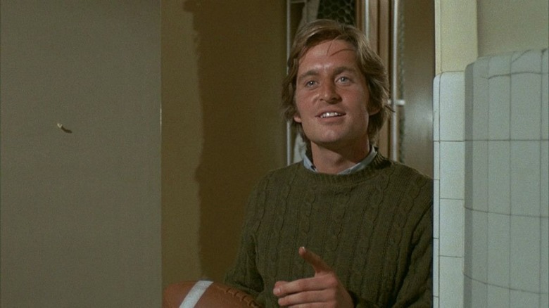 Michael Douglas in green sweater holding football