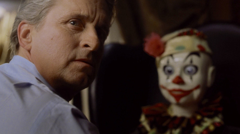 Michael Douglas looking over his shoulder with clown in background